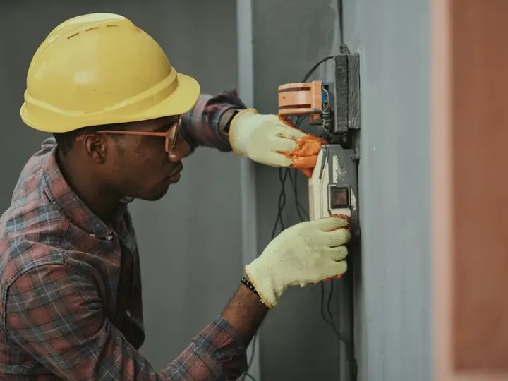 An electrician in a hard hat working on a meter