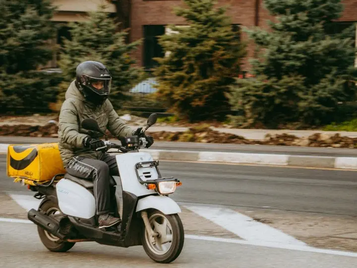 A rider on a scooter with a delivery box